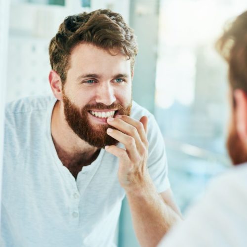 Mann som ser i speilet - slik kan du unngå syreskader på tennene. FOTO