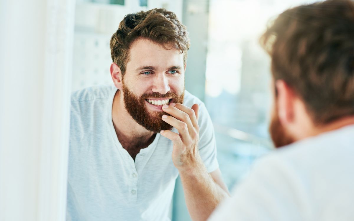 Mann som ser i speilet - slik kan du unngå syreskader på tennene. FOTO